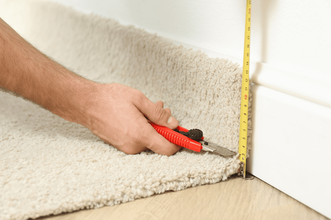 worker with cutting knife and measuring tape installing flooring