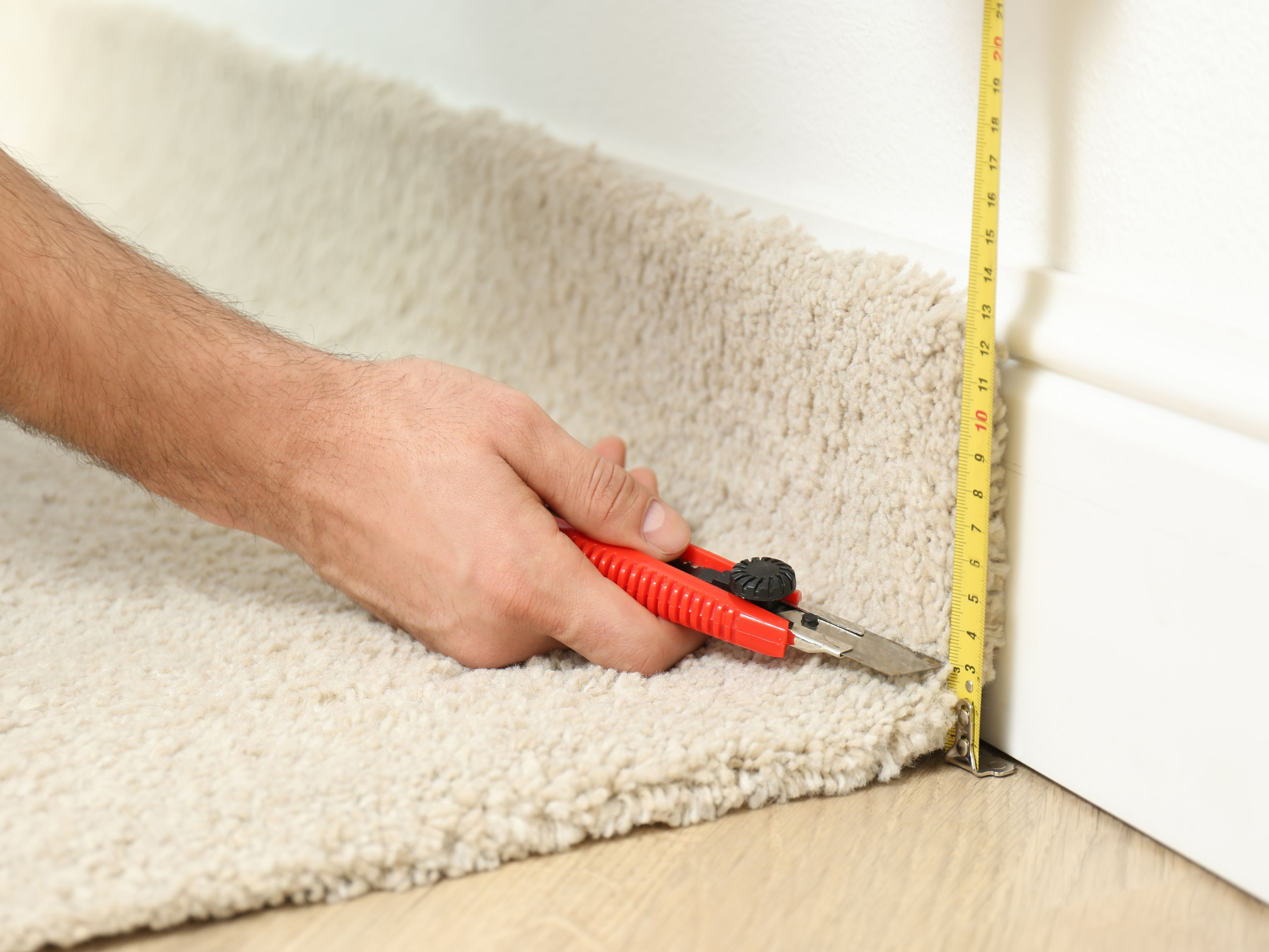 worker with cutting knife and measuring tape installing flooring